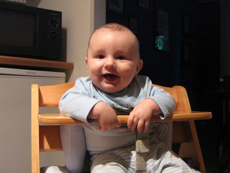 Merlin als Baby im Hochstuhl, lachend